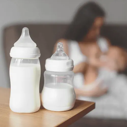 Jeannine Pech Logopädie - Mutter mit Baby im Hintergrund - Milchflaschen im Vordergrund